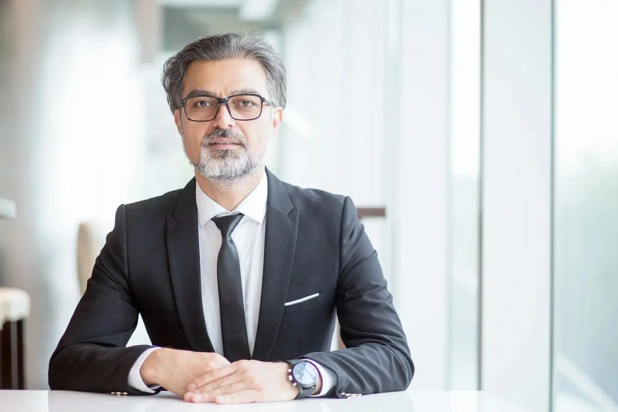 Closeup portrait of serious middle-aged handsome business man looking at camera and sitting at empty desk in office. Front view. (Closeup portrait of serious middle-aged handsome business man looking at camera and sitting at empty desk in office. Fron